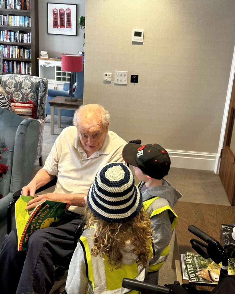 One of our Upton Mill care home residents enjoying a story read by local nursery children during a visit from Tetbury.