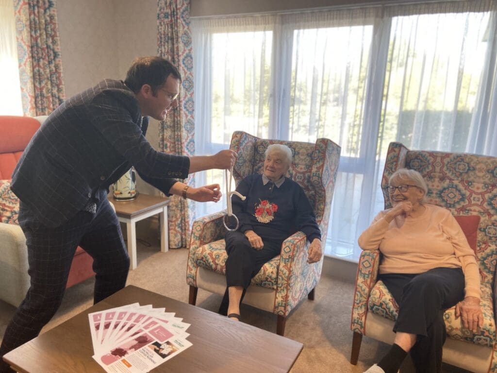 Magician Patrick Aitchison shows off some close-up magic totwo of our Deer Park residents, who sit comfortably as they laugh in wonder at his trick